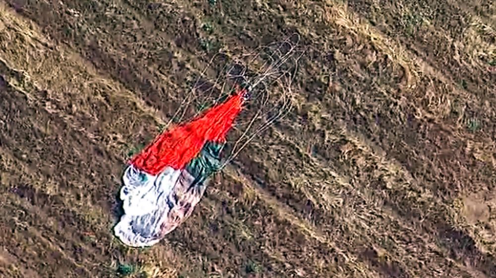 Pilotens fallskjerm ligger etterlatt på et jorde. Han overlevde etter å ha skutt seg ut av jetflyet sitt, som siden styrtet i et varehus.