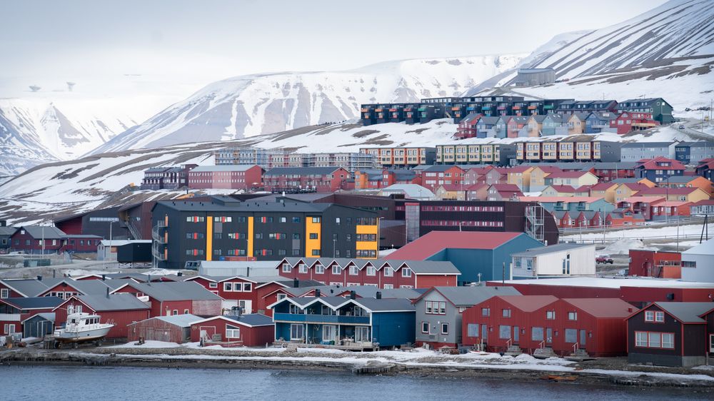 Bygningene i Longyearbyen synker mer enn de målte bygningene andre steder på Svalbard. UNIS' relativt nye gjestehus (grå og gul bygning midt i bildet) sank i fjor med 8 millimeter på flere av målepunktene.