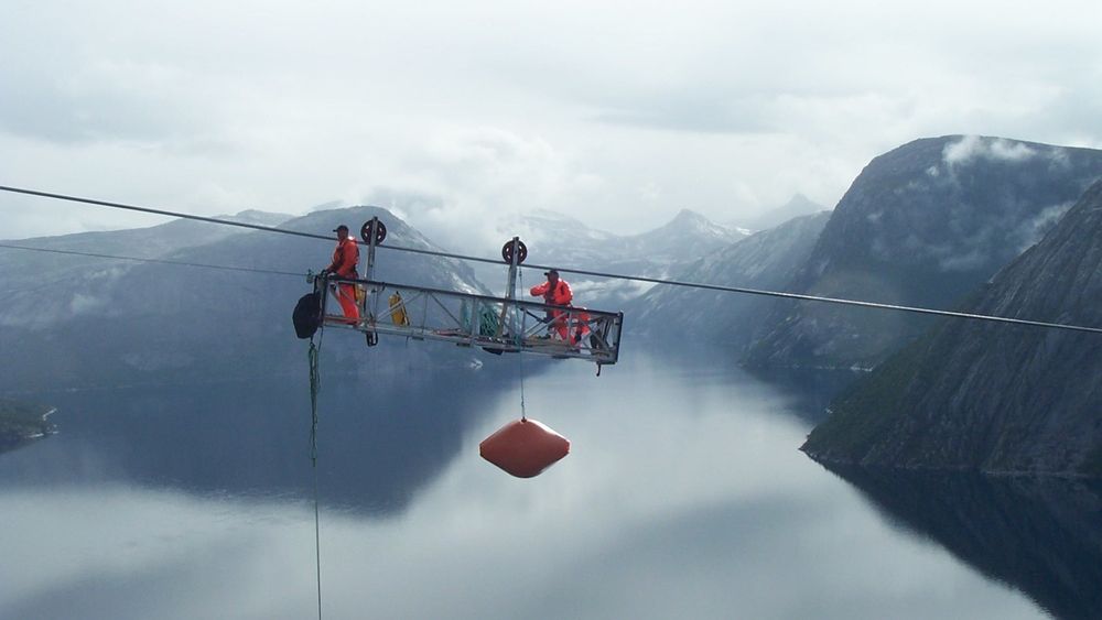 Man kan ikke ha høydeskrekk hvis man skal bygge eller vedlikeholde kraftlinjer. Men nå mener NVE og Energi Norge at også prisen er for høy. Bilder er fra utskifting av flymarkører over Hellemofjorden i 2003.