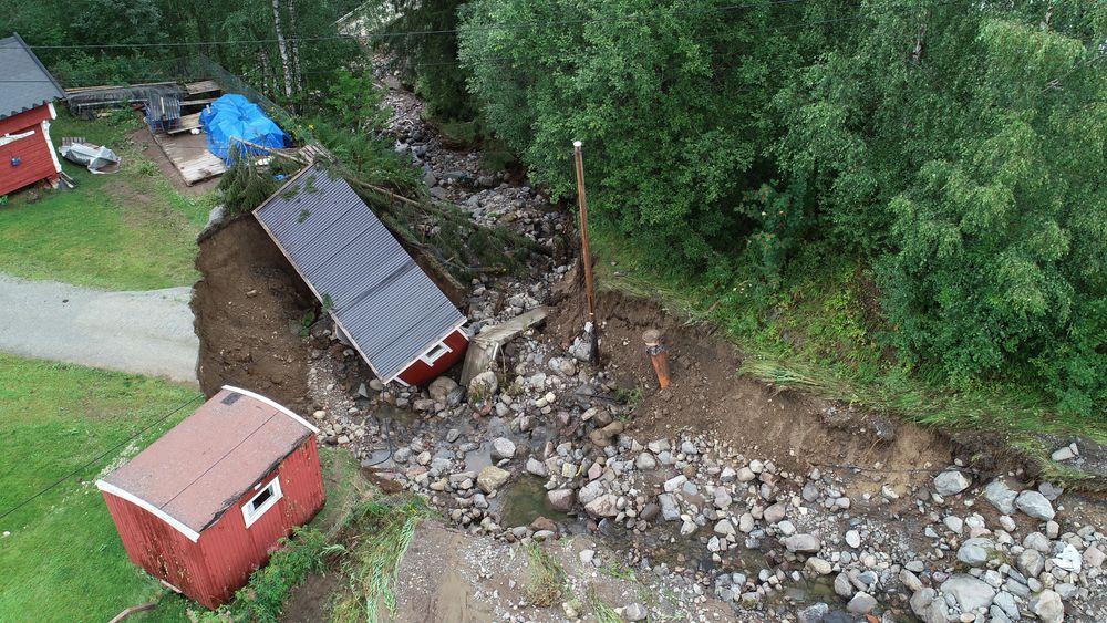 Store nedbørsmengder førte til flom og oversvømmelse i Brumunddal i sommer. Veien ble vasket bort og et uthus ble tatt av vannmassene.