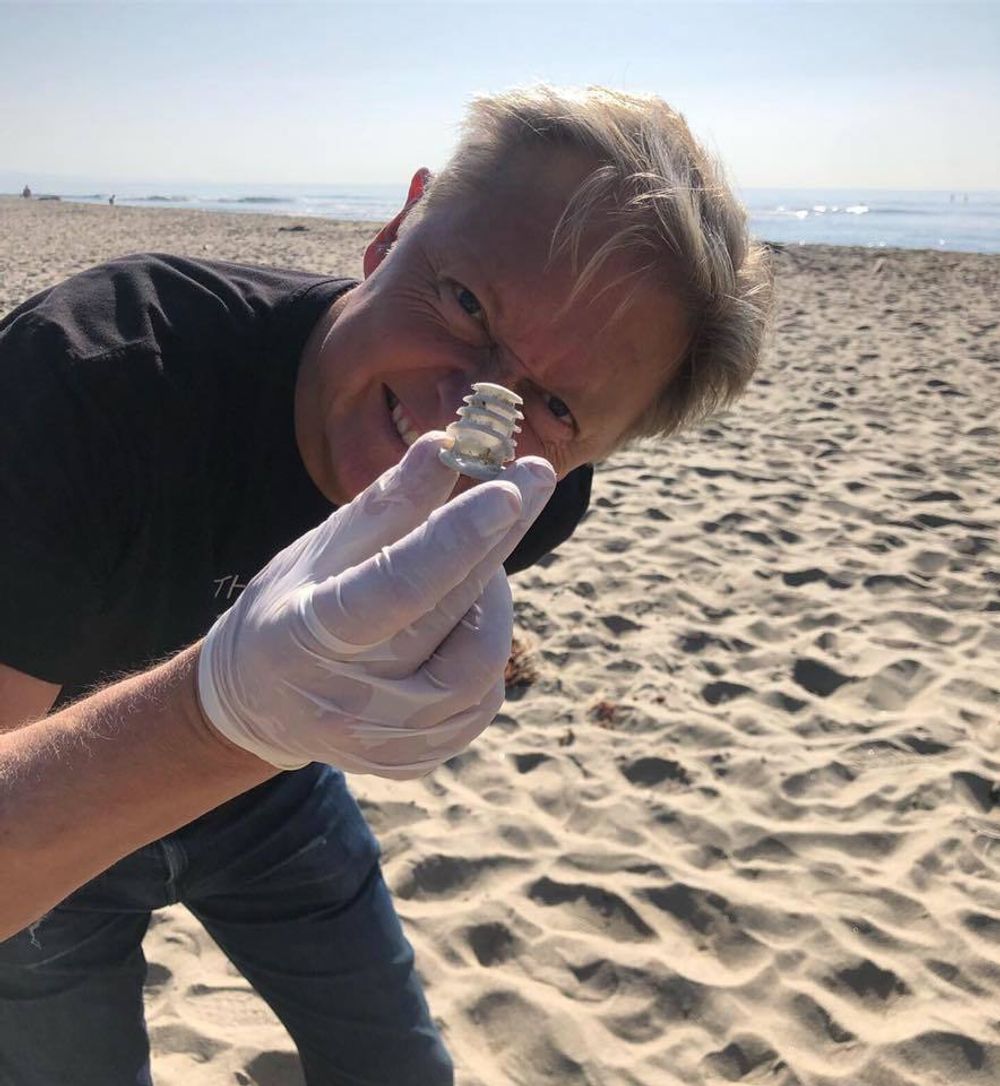 Henrik Fisker plukker havsøppel på stranden i Malibu. Hans nye elbil skal blant annet gjenbruke gamle fiskegarn.