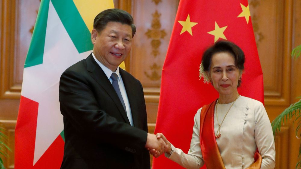 Myanmars sivile leder Aung San Suu Kyi og den kinesiske presidenten Xi Jinping tar hverandre i hånden under toppmøtet.