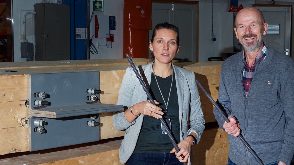 Forskningsleder Petra Rüther fra Sintef og professor Kjell Arne Malo fra NTNU foran bæresøyler for de nye dekkene. Innfestingen skjer med Ø22mm gjengestenger og stålbraketter.     