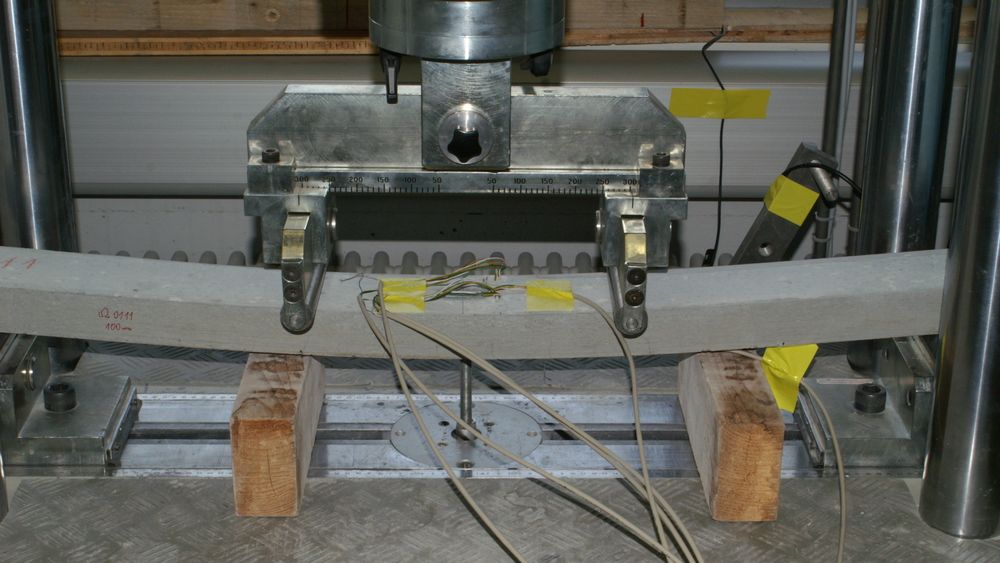 En liten bjelke produsert med karbonarmering og ekspanderernde betong blir utsatt for en bøyetest i laboratoriet til Empa.