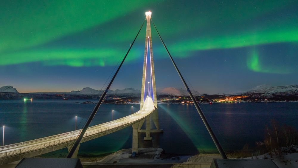 Hålogalandsbrua opplyst av både kunstig diode-lys og naturens fargepalett.