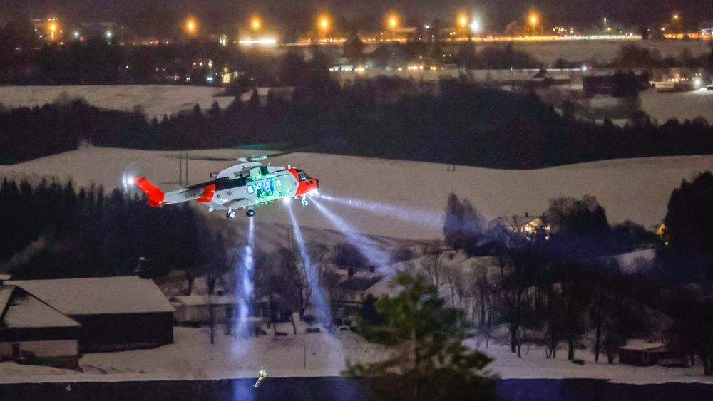 En person senkes ned fra et redningshelikopter over skredområdet i Ask onsdag kveld. Redningsarbeidet fortsetter utover natten.