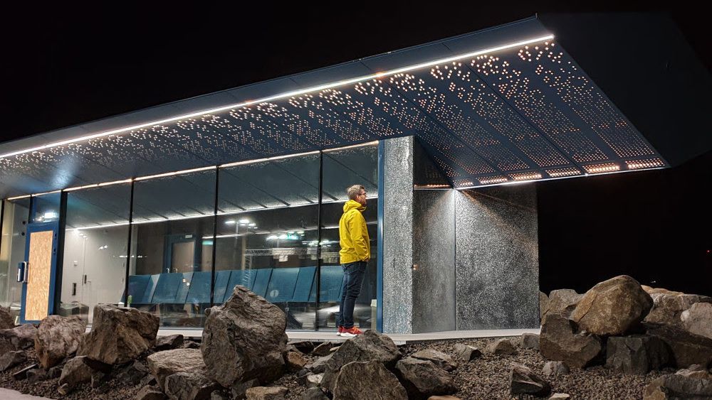 Belysningen av Moskenes Servicebygg i Lofoten henter inspirasjon fra naturen rundt. Skiftninger i lysets farge, lyshet og mengde bidrar til at dette blir en futuristisk og moderne lysinstallasjon, mener juryen.