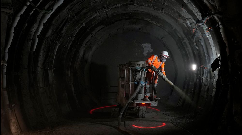 En arbeider sprayer et lag med sement som beskyttelse i en tunnel for radioaktivt avfall i Bure.