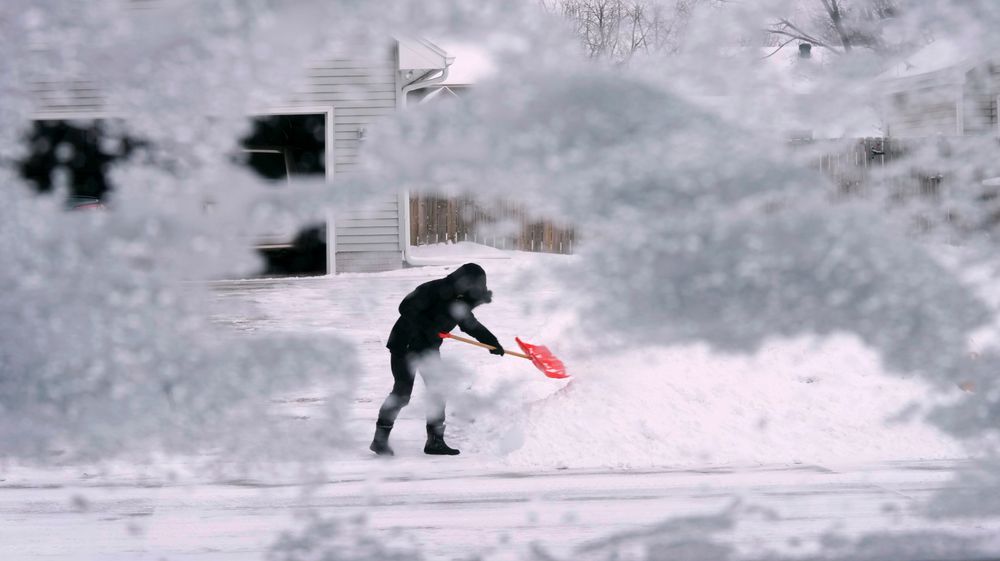 En mann prøver å skuffe unna snøen i Urbandale, Iowa. USA og Canada er midt i et skikkelig vinteruvær.