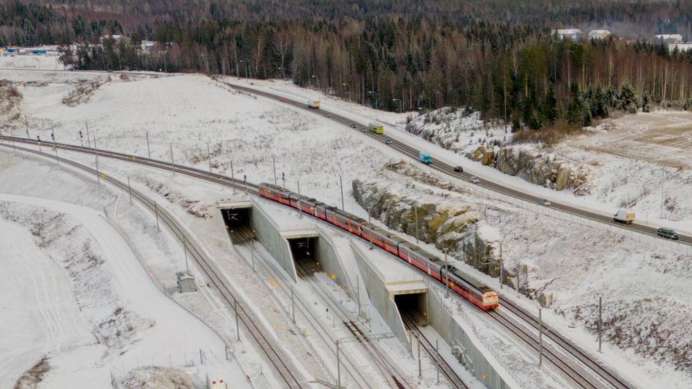 Et tog kjører på Østfoldbanen over inngangene til Blixtunnelen og Roåstunnelen fra Ski i retning mot Oslo S. Follobanen ble åpnet 12. desember, men ble stengt åtte dager senere etter en brann i et koblingshus på Ski stasjon.