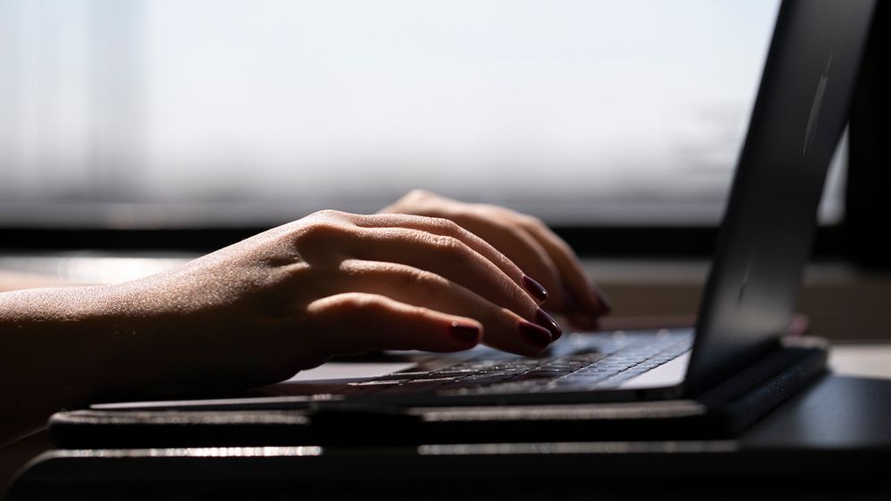 FILE - This May 18, 2021, photo shows a woman typing on a laptop on a train in New Jersey.  Scams ar ...