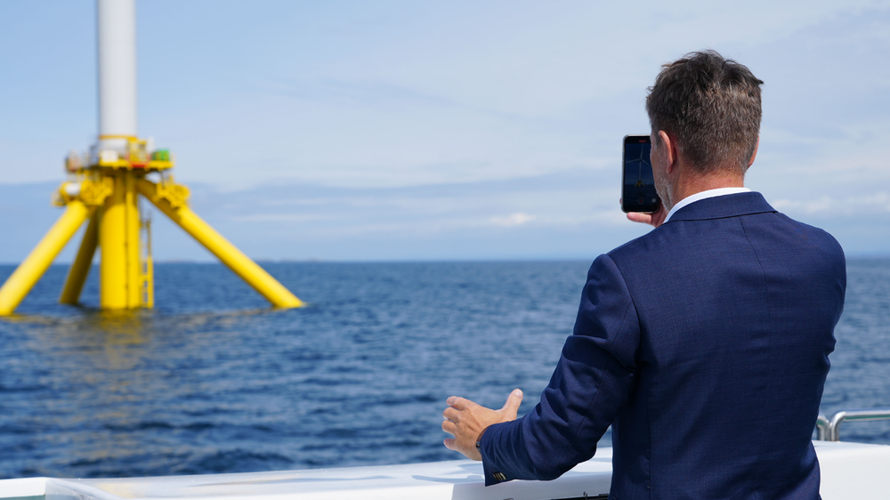 Olje- og energiminister Terje Aasland tar bilde av en havvind-turbin på METCentre utenfor Karmøy.