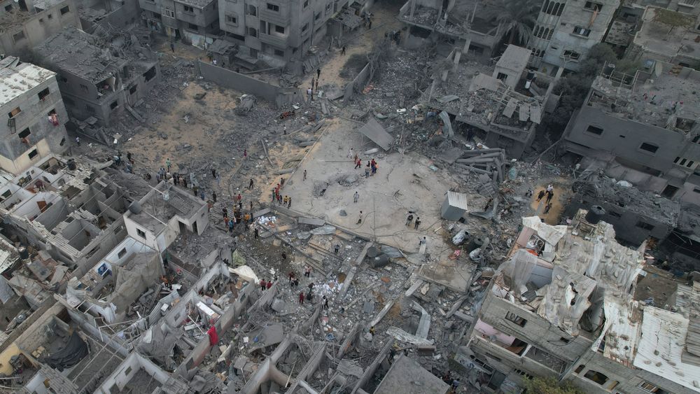 Folk på Gazastripen ser på ødeleggelsene i Nusseirat-flyktningleiren etter israelske luftangrep søndag.