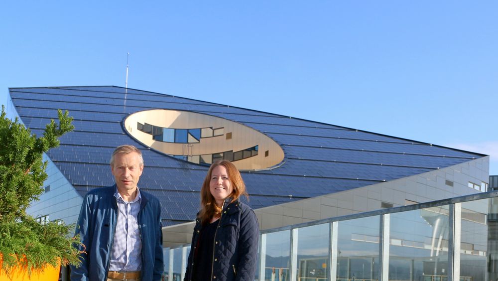 Klaus Livik og Marit Myrstad i Trondheim kommune foran Powerhouse, et bygg som er utstyrt med solceller over det hele og som produserer mer strøm enn det forbruker.