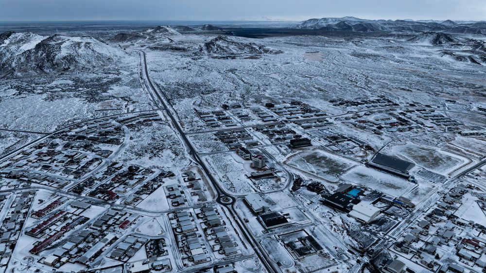 Lavaområdet som har oppstått i forbindelse med den seneste vulkanske aktiviteten kan skimtes i bakgrunnen av Grindavik på halvøya Reykjanes. Bildet er tatt 21. desember i fjor.