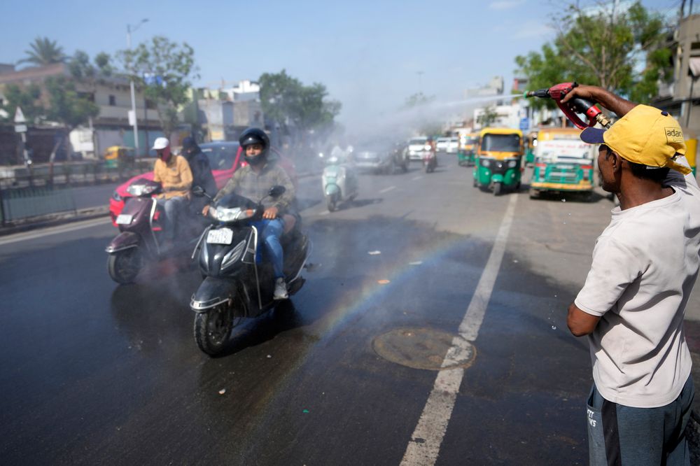 En mann sprayer vann på pendlere for å kjøle dem ned i byen Ahmedabad i India.