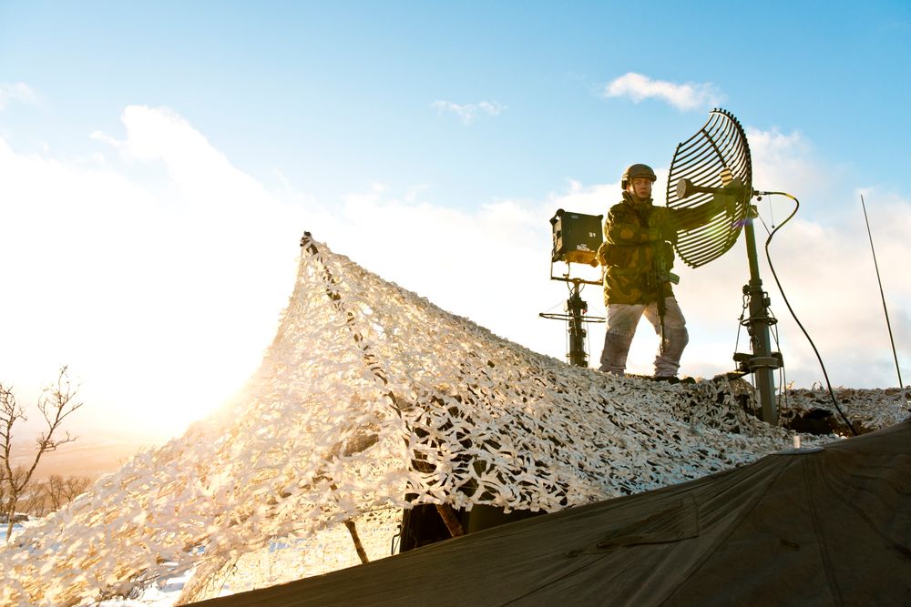 En soldat i Sambandsbataljonen justerer på en UHF-antenne under en øvelse i 2013. Det blir stadig mer elektrisk utstyr i felt. Nå ser FFI etter en løsning som kan kutte ned på antall adaptere og kabler.
