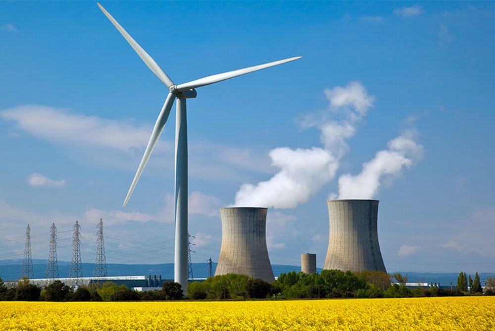 Bildet viser Tricastin Nuclear Power Plant i Saint-Paul-Trois-Châteaux i Frankrike. Der ligger kjernekraftverket ved siden av vindturbiner. 