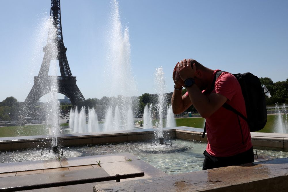 En turist kjøler seg foran Eiffeltårnet i Paris denne uken.