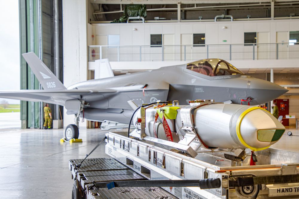 Et JSM-missil (Joint Strike Missile) ligger på en tralle foran et F-35-fly i en hangar på Ørland flystasjon i april 2025.