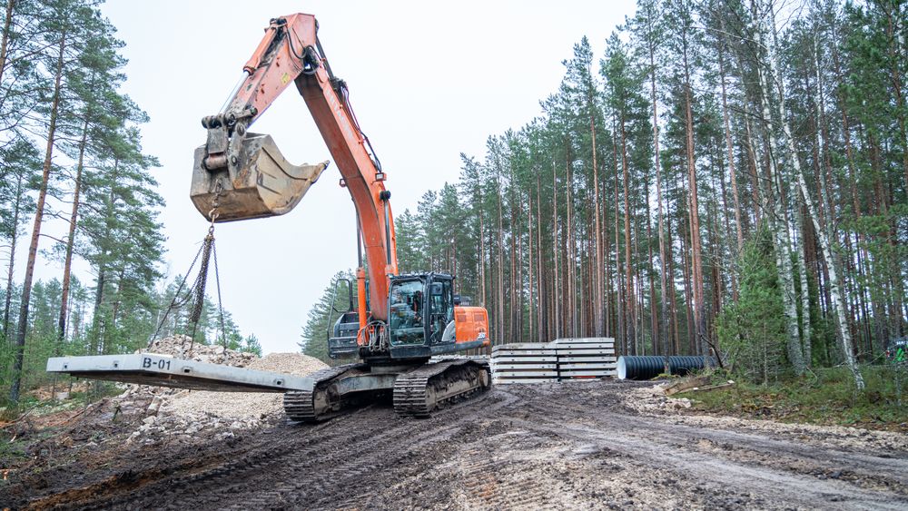 En gravemaskin løfter en tjukk betongplate under bygging av bunkere i Estland i desember 2025.