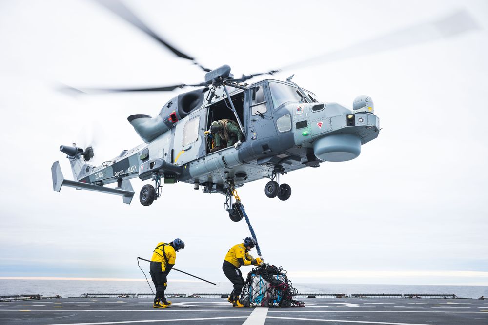 Et britisk Wildcat-helikopter henter en last på helikopterdekket til den norske fregatten KNM Thor Heyerdahl.