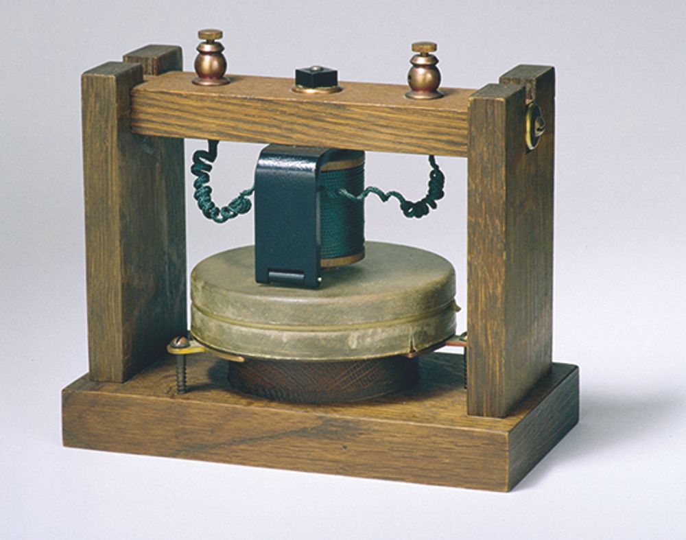 Alexander Graham Bell var først med å ta patent på et apparat som muliggjorde samtaler over distanse mellom personer. Hans prototyp fra 1876 (her vist opp ned) brukte ikke elektrisitet og hadde svært begrenset rekkevidde. 