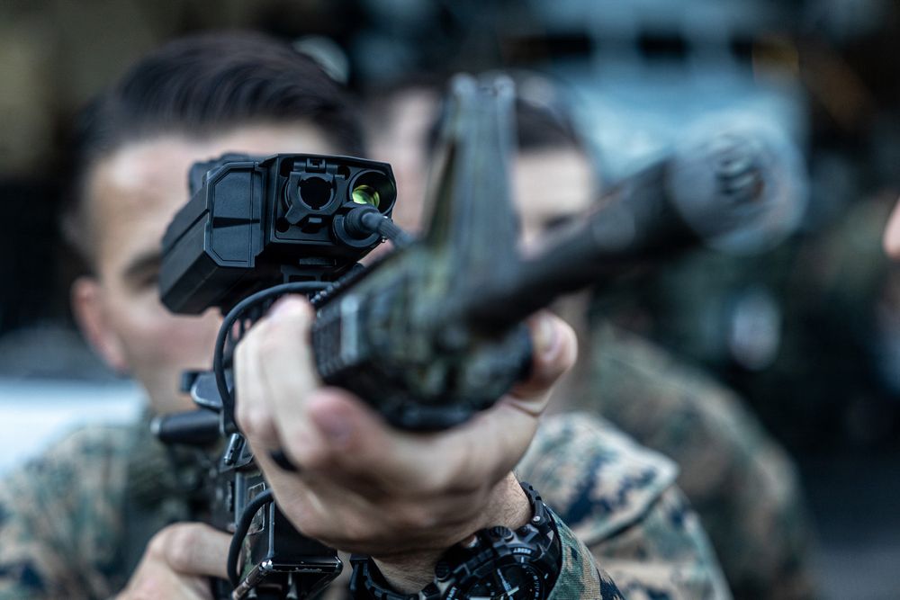 En soldat i U.S. Marine Corps sikter med et M4-gevær mot en drone. På toppen av geværet sitter det et avansert sikte som skal hjelpe skytteren med å avgjøre når skudd bør avfyres. 