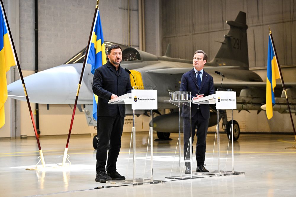 Ukrainas president Volodymyr Zelenskyj og Sveriges statsminister Ulf Kristersson under en pressekonferansen torsdag. I bakgrunnen  står et moderne Gripen E-fly, den typen som Ukraina planlegger å kjøpe.