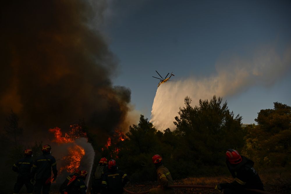 Et brannhelikopter slipper ned vann på en røykfyllt skog under en skogbrann nær Porto Germeno, nordvest for Aten i Hellas søndag 2. august.
