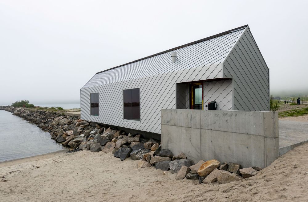 Det nye servicebygget er langstrakt, med en form hentet fra tradisjonelle sjøhus på Senja. Arkitekt: Nordic Office of Architecture.
