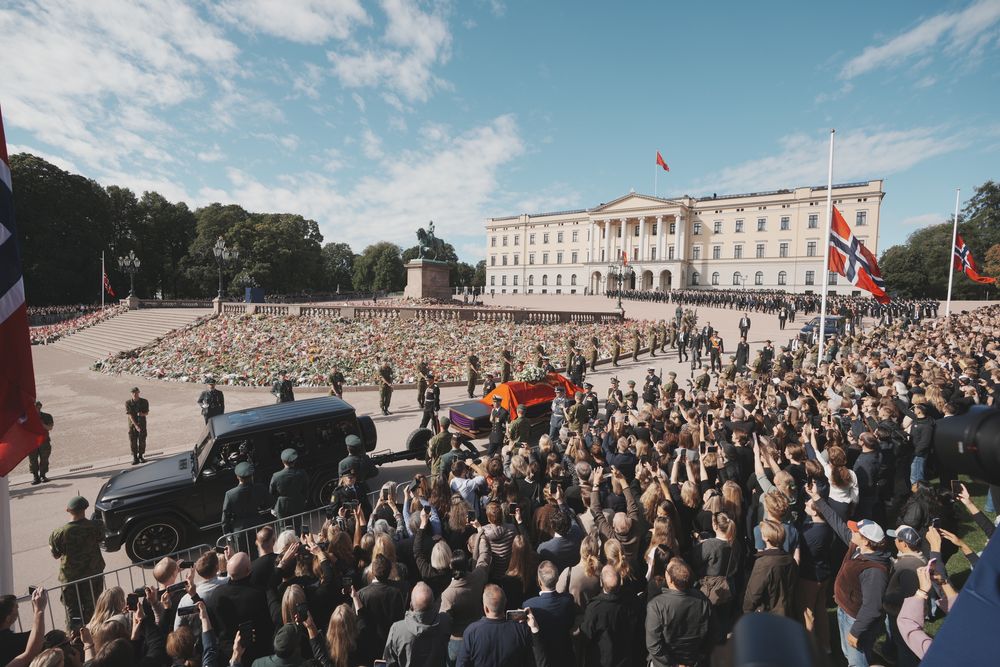 Båren med kong Harald står på en kanonlavett som trekkes av en svart Mercedes-Benz Geländewagen, flankert av bårebærere fra kongens adjutantstab.