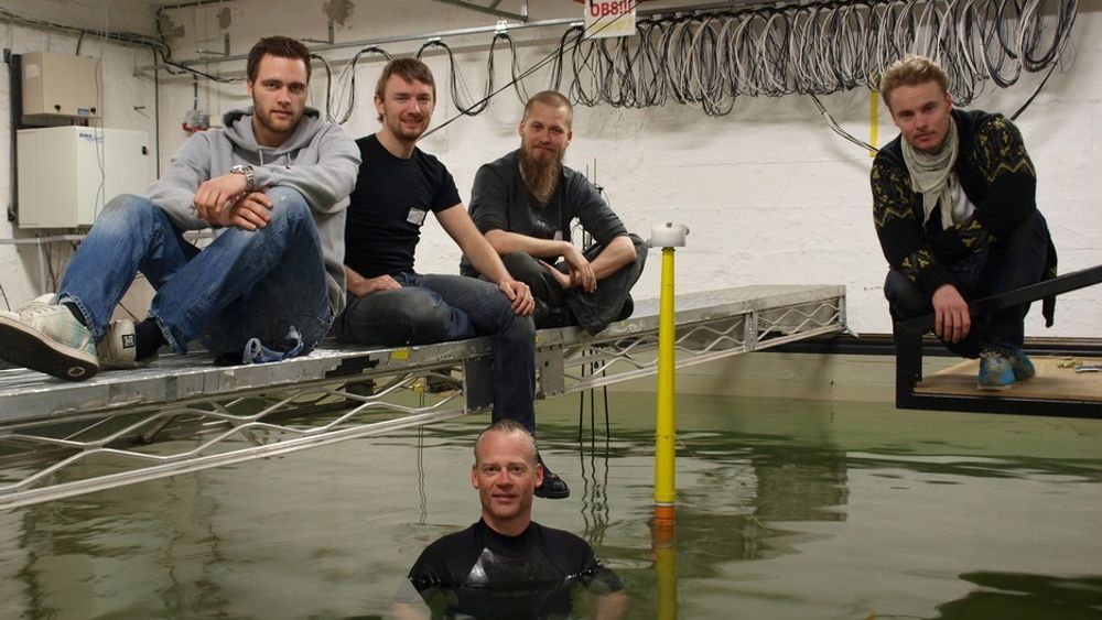 TESTES I VANNET: UMB-gruppen har testet ut den nye flytende vindturbinen i bølgebassenget til MARINTEK/SINTEF. Bak fra venstre: Fredrik Even Hansen, Anders Myhr, Karl Jacob Maus og Ulrik Aimar Møller. I vannet, ved Njord-modellen, er professor Tor Anders Nygaard.