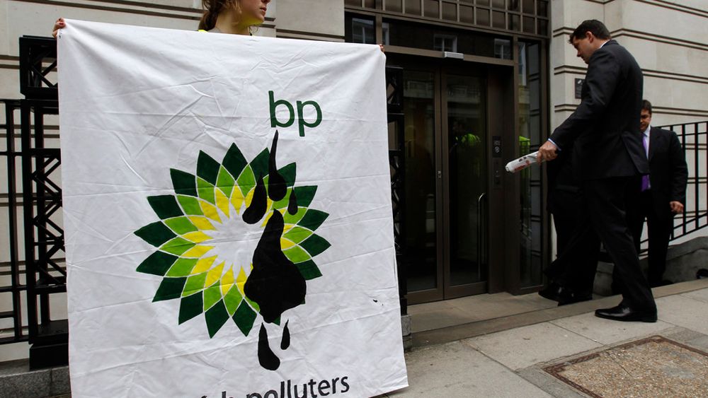 En Greenpeace-aktivist holder opp en banner foran BPs hovedkontor i London torsdag.