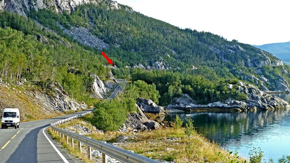 Den røde pilen markerer tunnelinnslaget i sørvest. Vegen langs fjellsiden i bakgrunnen blir stengt når tunnelen åpnes 12.12.1012.