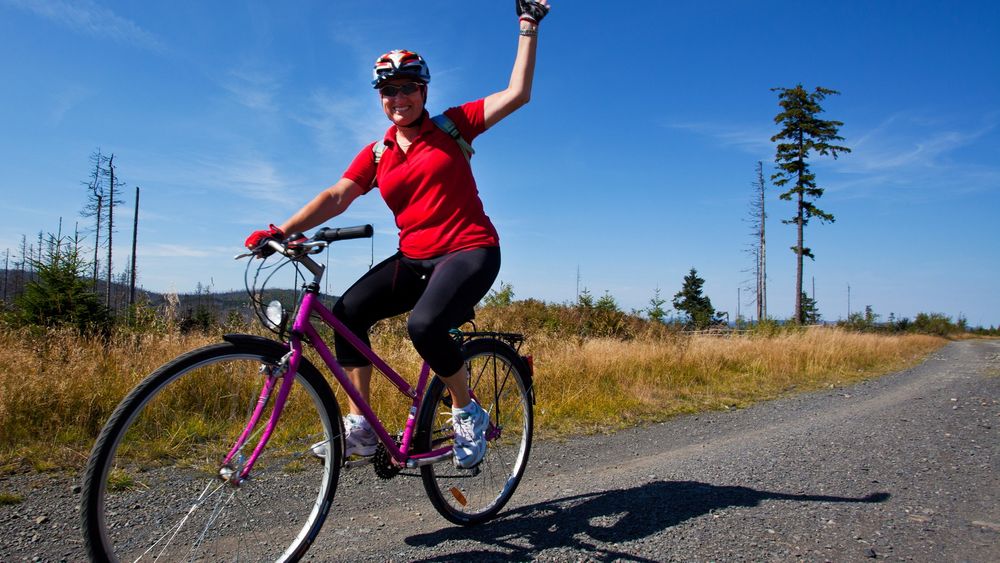 Happy woman riding a bike in a countryside 