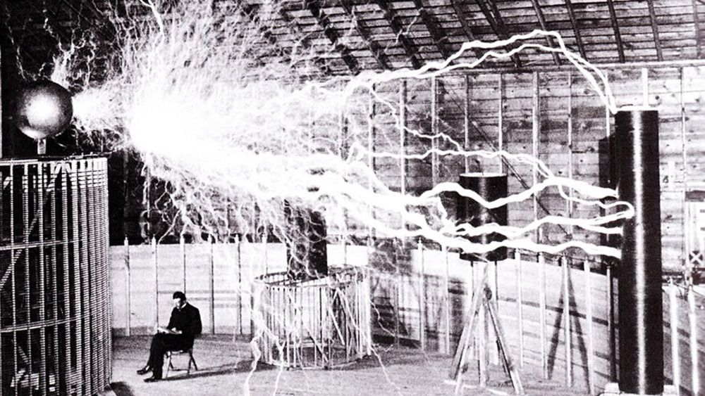 Nikola Tesla i laboratoriet i Colorado Springs, desember 1899. Bildet er dobbeleksponert - de elektriske strålene er tatt i et mørkt rom, mens Tesla og rommet er eksponert i etterkant.  