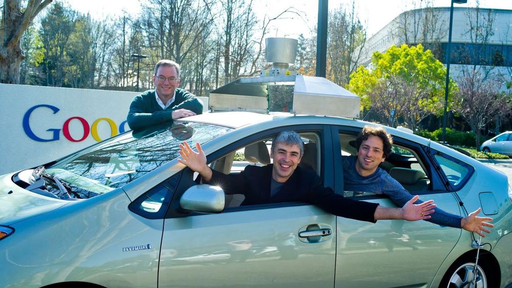 Larry Page i førersetet på Googles miljøbil fra 2011. I baksetet sitter medgründer Sergey Brin, mens styreformann Eric Schmidt står bak bilen.