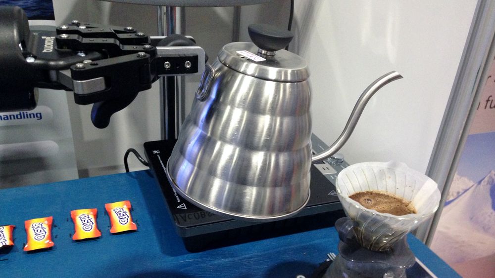 Roboten i gang med å helle kokende vann over nykvernet kaffe.