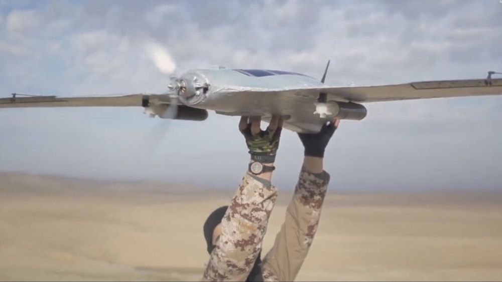 Et stillbilde fra en IS-video, hvor en kriger er i ferd med å sende en drone av gårde med granater under vingene.