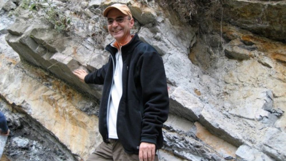Daniel Rothman med høyre hånd plassert på et lag ved Xiakou i Kina. Laget markerer overgangen mellom de geologiske periodene perm og trias for cirka 252 millioner år siden, da nærmere 96 prosent av alle levende arter i havet døde ut.