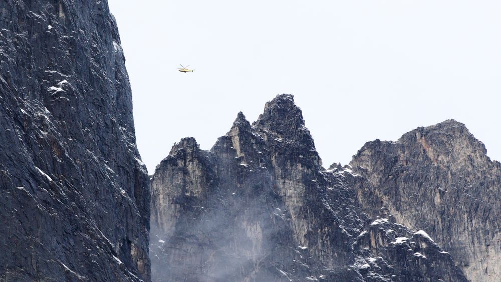 Et helikopter flyr over fjellene rundt Veslemannen i fjellpartiet Mannen i Rauma kommune i Møre og Romsdal.