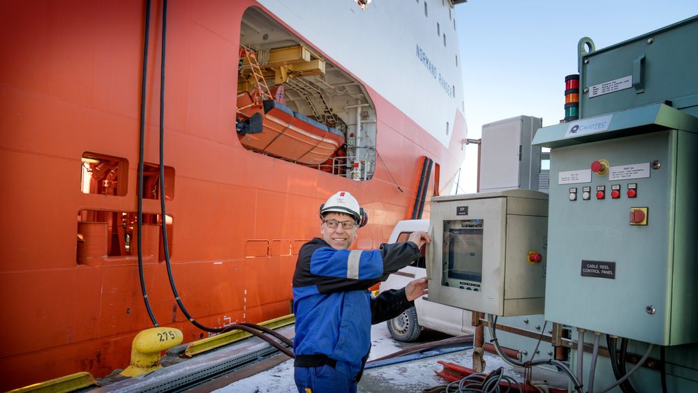 Ankerhåndtereren Normand Ranger kobler seg på landstrømanlegget på Skoltekaien i Bergen. Elektriker Jarl Svoren må inn i skapet og koble til strømmen.