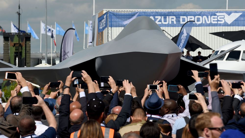 Visitors watch the unveiling ceremony of the full-scale jet fighter model of the Systeme de Combat Aerien Futur (SCAF), the French-German-Spanish new generation Future Combat Air System (FCAS), during the 53rd International Paris Air Show at Le Bourget Airport near Paris, on June 17, 2019. (Photo by ERIC PIERMONT / AFP)