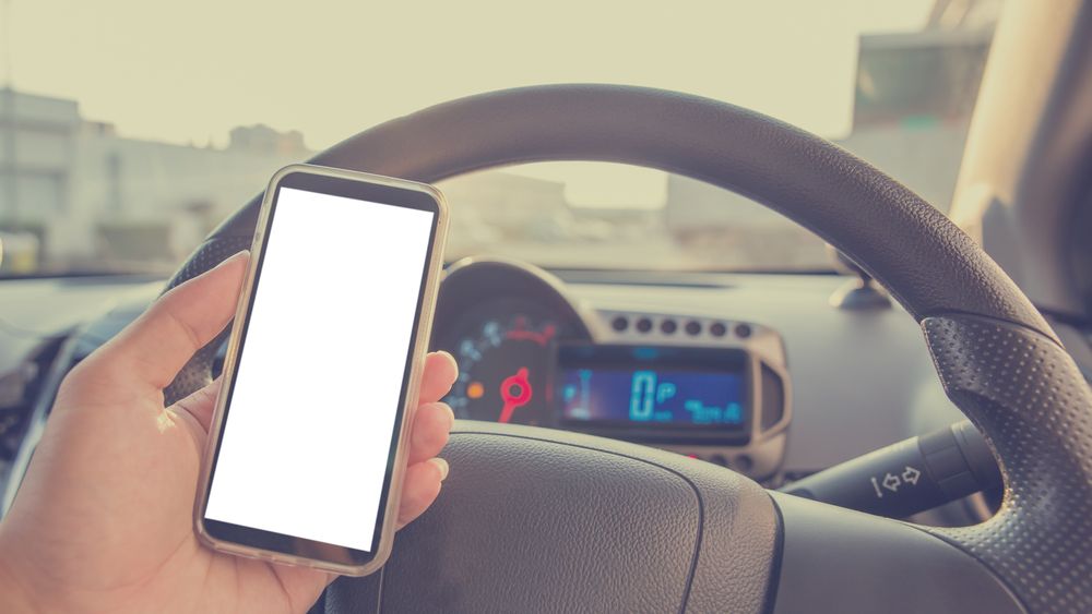 Using cellphone in car with defocused city traffic. Vintage filter.