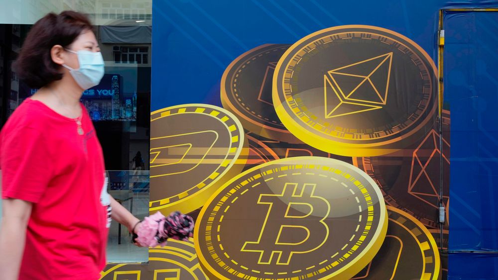 En kvinne går forbi en Bitcoin-reklame i Hongkong. 