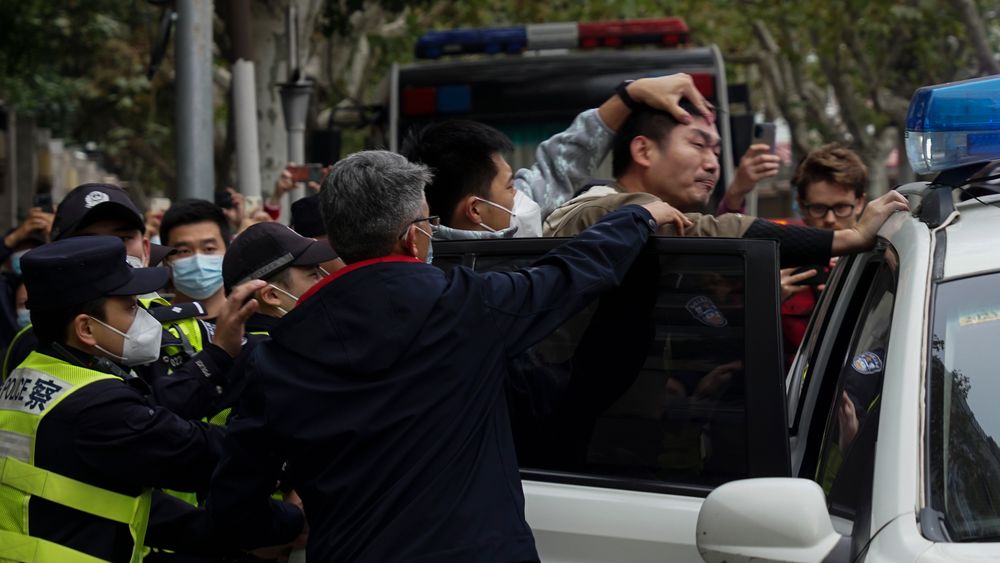 En demonstrant tvinges inn i en politibil i Shanghai. Mange demonstranter spores av politiet.