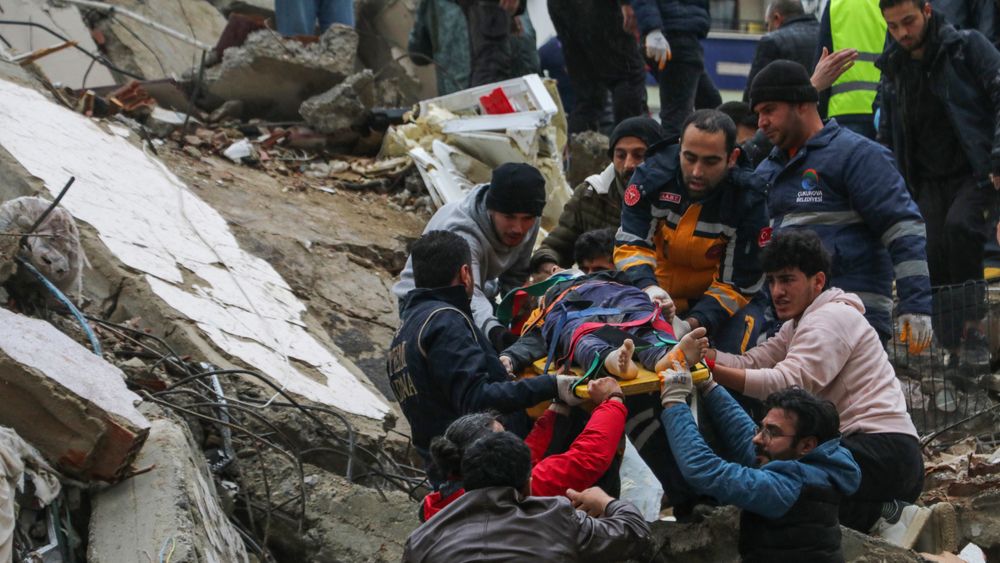 Redningsarbeidere jobber med å hente ut ofre fra en sammenrast bygning i Adana i Tyrkia.