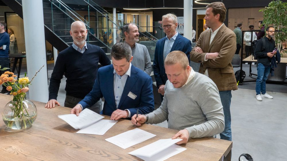 Senioringeniør Håkon Eyde Kjuus i Forsvarsmateriell og administrerende direktør Eivind Helgaker i Ice signerer samarbeidsavtale under påsyn av fornøyde medarbeidere fra Ice og Forsvarsmateriell.
