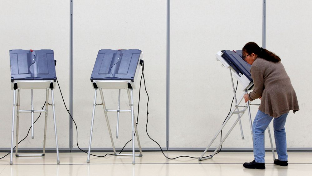 En frivillig setter opp stemmemaskiner på en barneskole i Newark i USA under presidentvalget i USA i 2012. I Norge praktiseres kun papirbaserte systemer i dag.